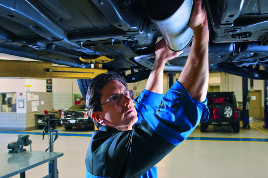 Technician working under car exhaust system